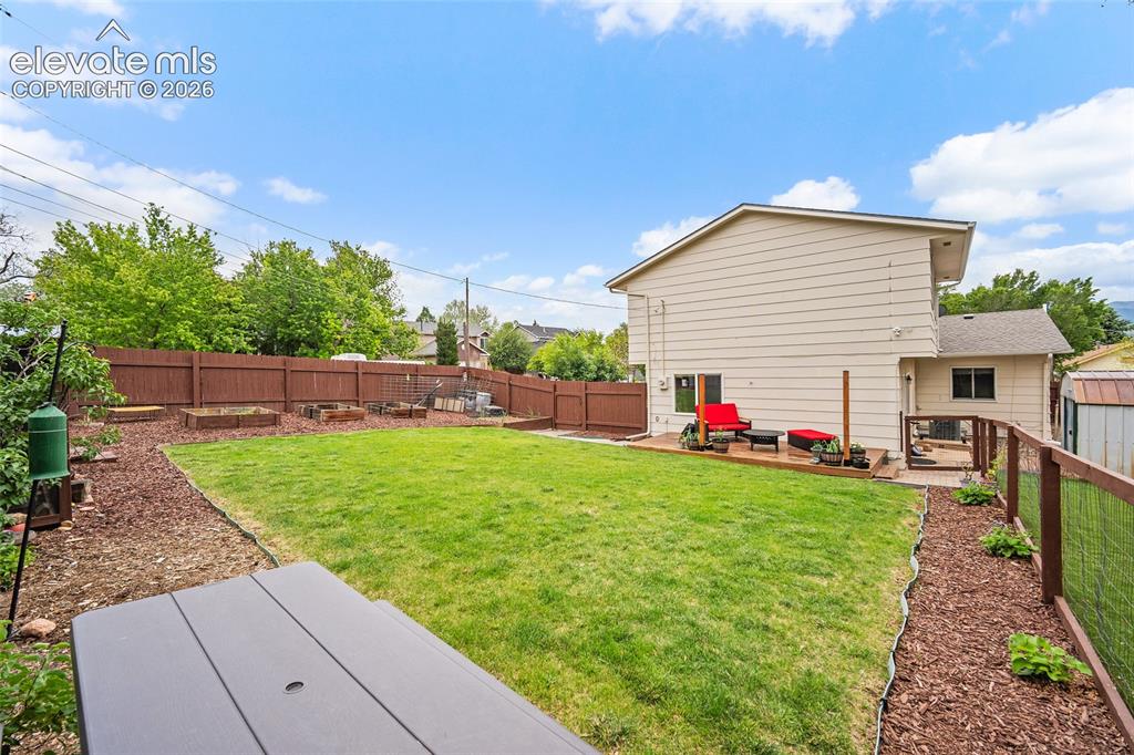 Image 36 of 44: Expansive backyard featuring a manicured lawn, a wooden privacy fence, and