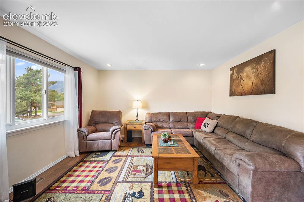 Image 5 of 44: Bright living area featuring wood-finish flooring, a large window, recessed