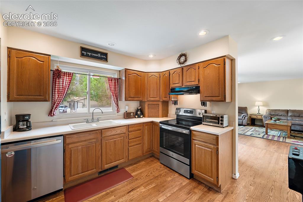 Image 6 of 44: Kitchen featuring wood-finish flooring, oak cabinetry, stainless steel rang