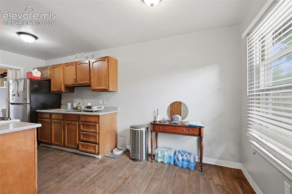 Image 11 of 32: Kitchen and dining area featuring wood-finish flooring, wood cabinetry, lig