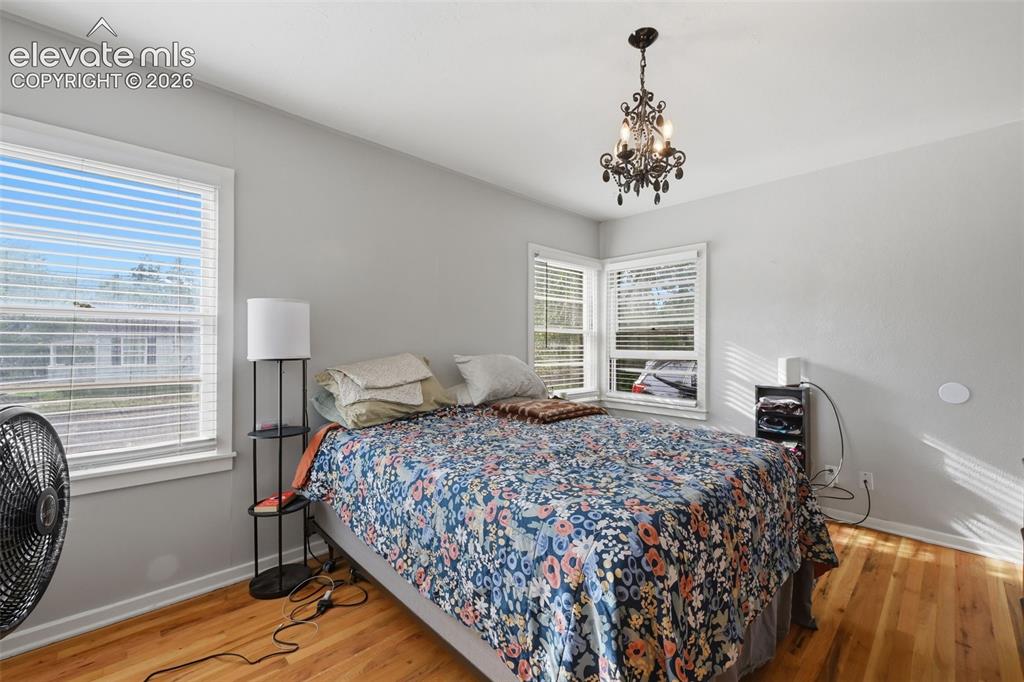 Image 15 of 32: Hardwood-finish flooring, two window units, and an ornate chandelier