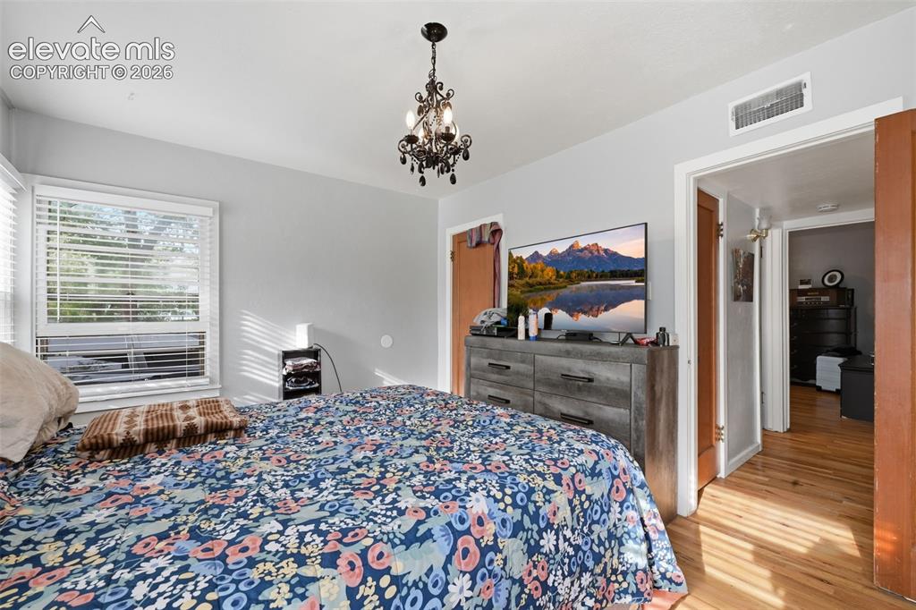 Image 16 of 32: Hardwood flooring, architectural chandelier, and a window with blinds
