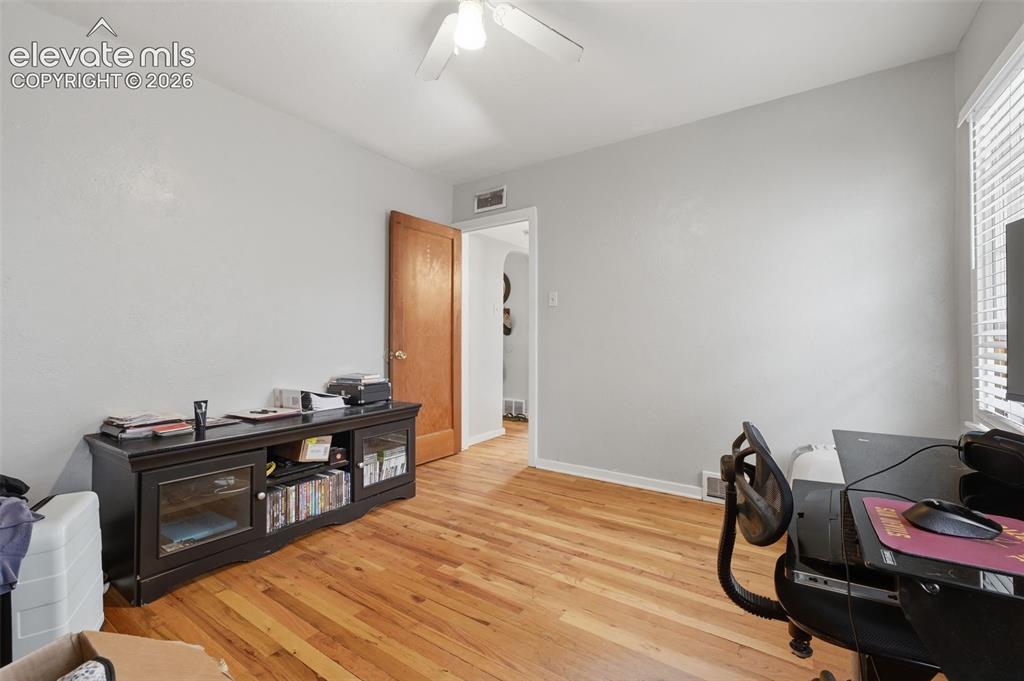 Image 20 of 32: Wood-finish flooring, white ceiling fan, and window with blinds