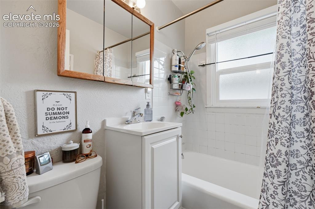 Image 23 of 32: White vanity with integrated sink, wood-framed medicine cabinet, and white