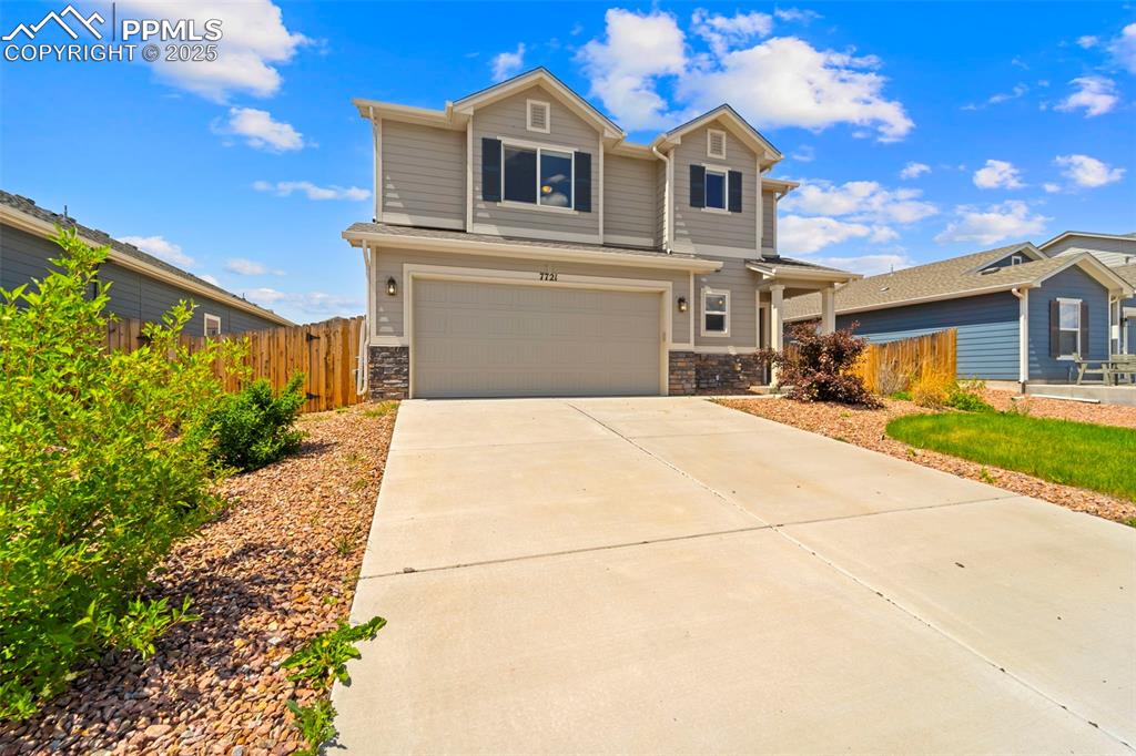 Image 11 of 35: View of front of home featuring a garage, stone siding, and driveway