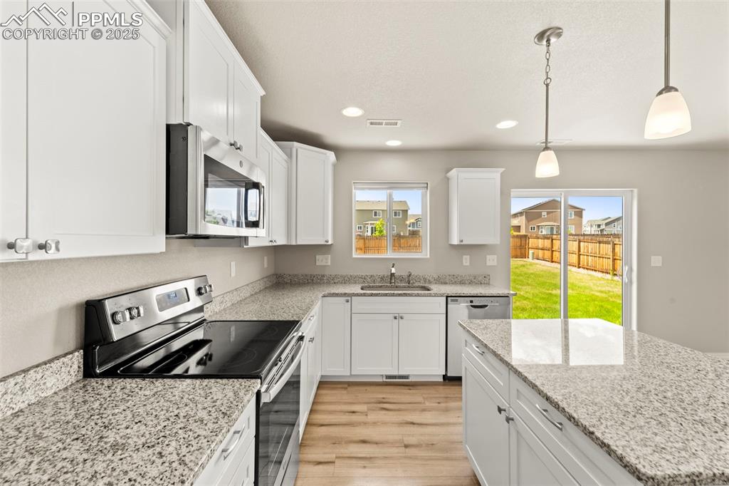 Image 21 of 35: Kitchen featuring appliances with stainless steel finishes, white cabinetry