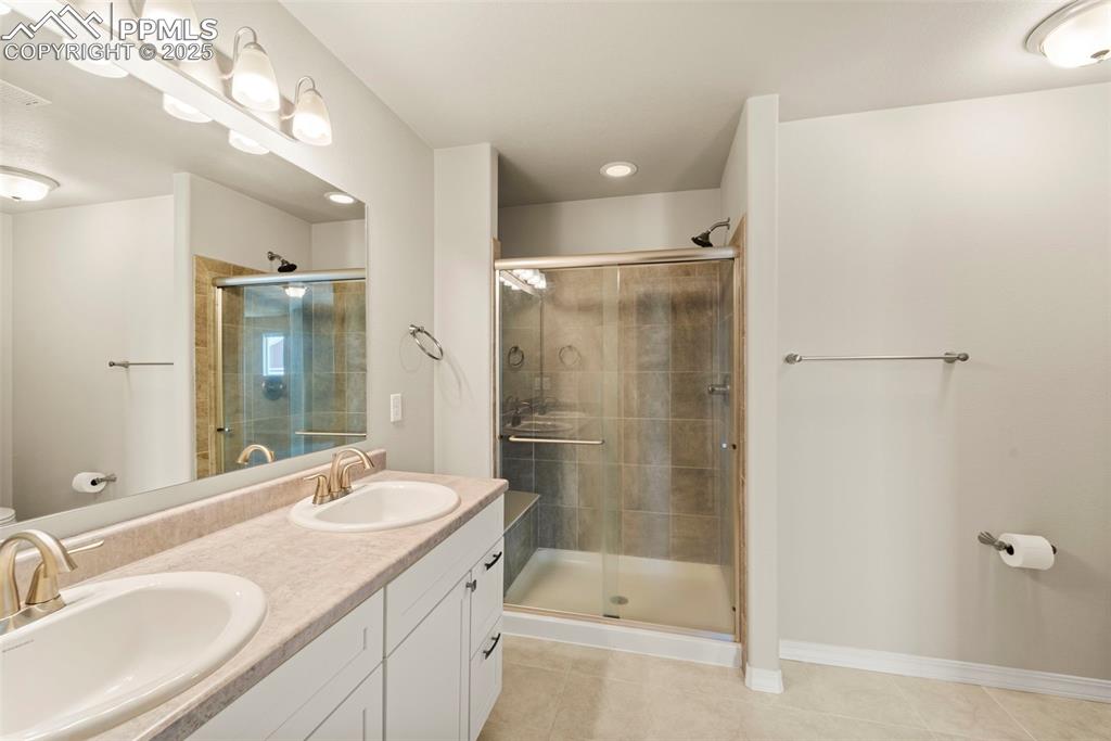 Image 35 of 35: Full bathroom featuring tile patterned floors, a stall shower, double vanit