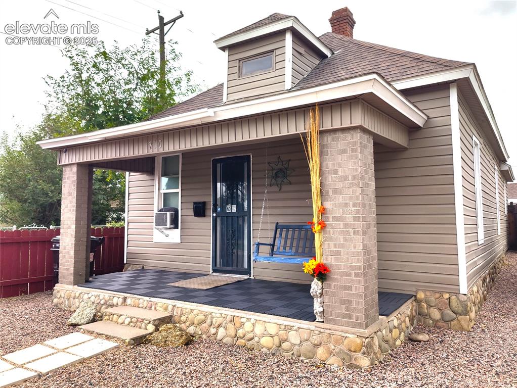 Caption: Covered porch featuring brick columns and checkerboard flooring