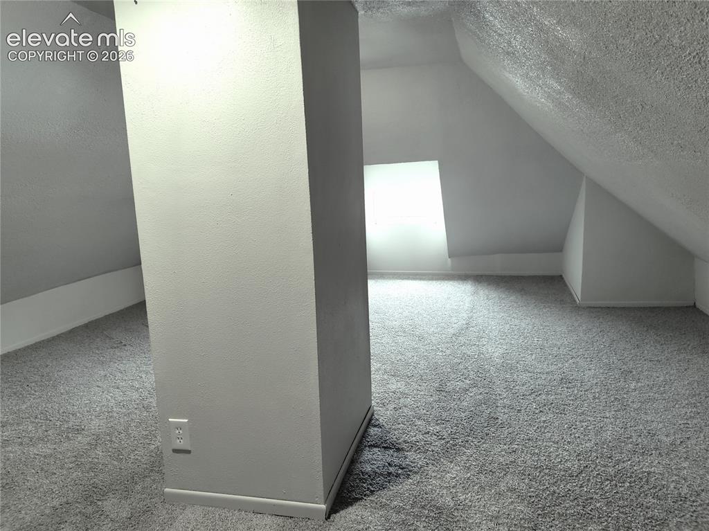 Image 12 of 13: Carpeted flooring with sloped ceilings and a rectangular window