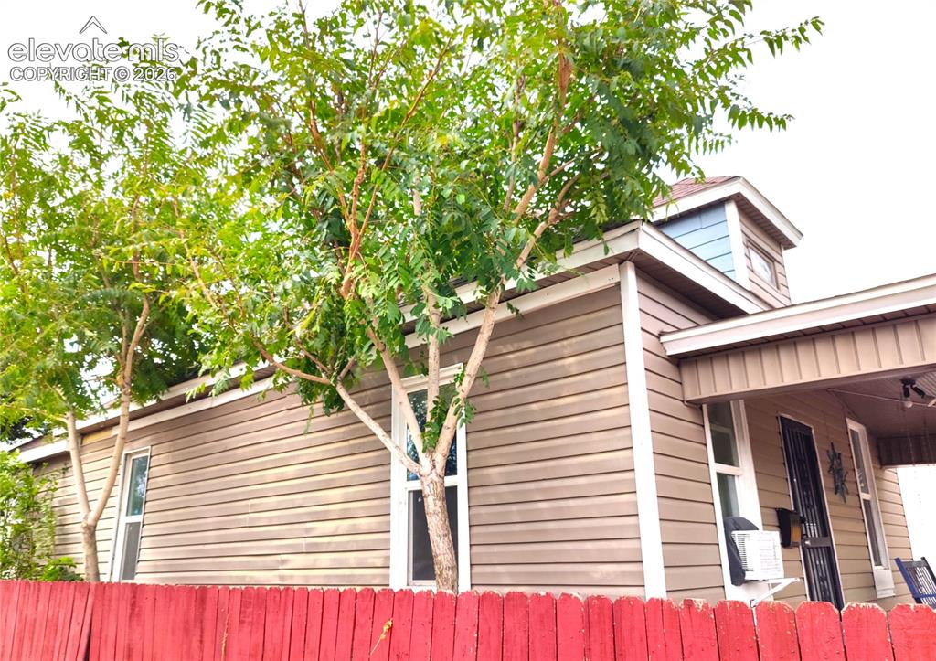 Image 3 of 13: Horizontal siding exterior with white trim, covered porch, and red picket f