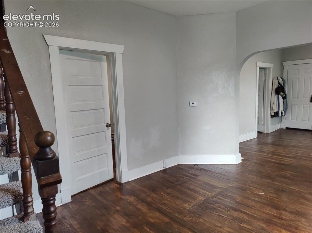Image 5 of 13: Wood-finish flooring, white trim, and a paneled interior door