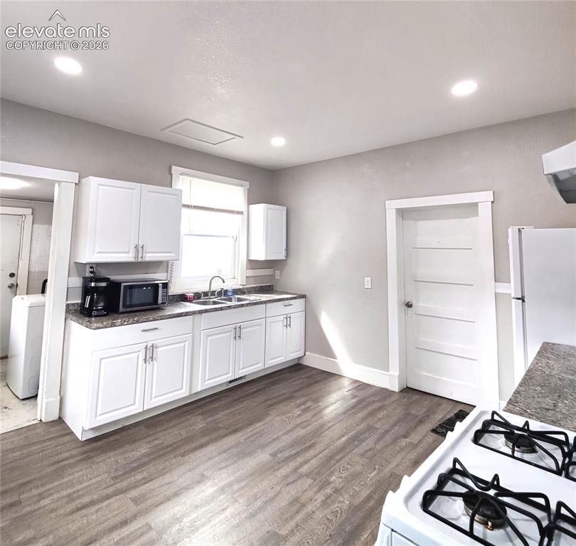 Image 7 of 13: Kitchen featuring wood-finish flooring, white cabinetry, a double basin sin