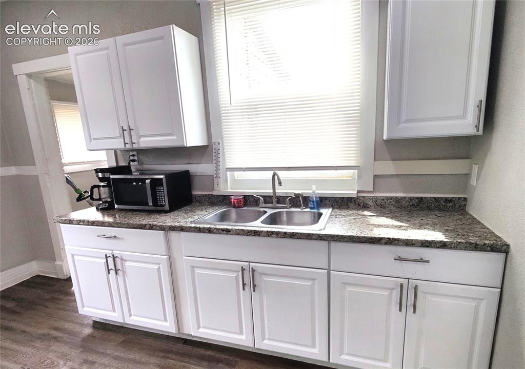 Image 8 of 13: White shaker-style cabinetry, double basin stainless steel sink, speckled c