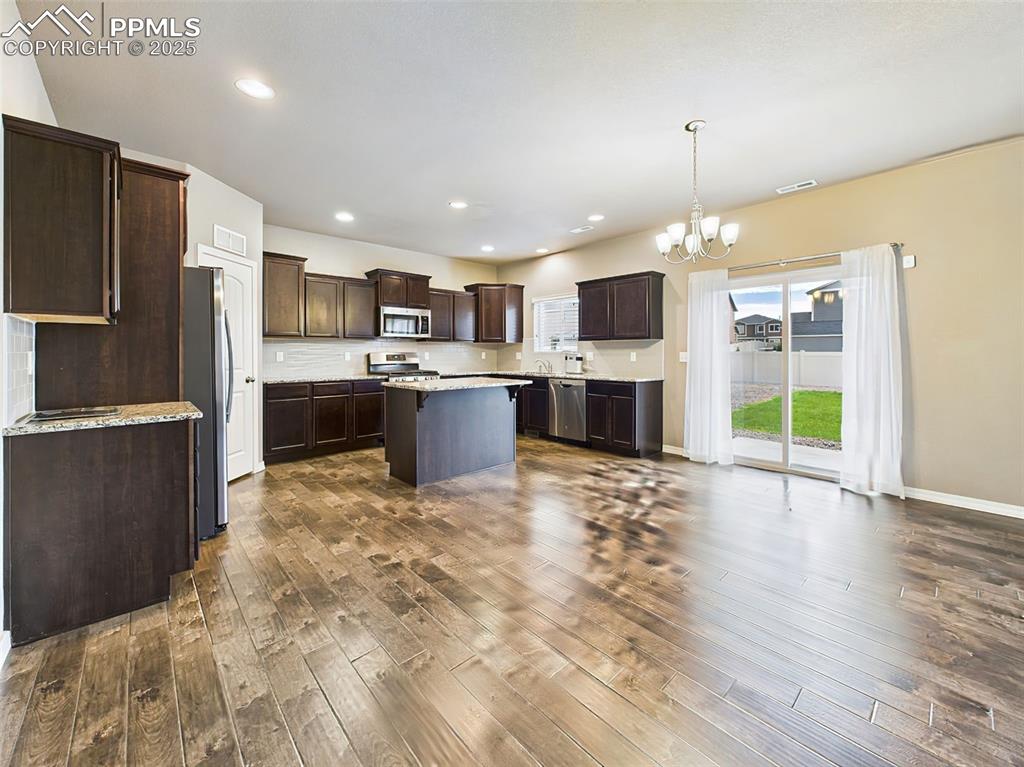 Image 12 of 50: Spacious dining area with rich LVP floors, modern chandelier, and sliding g
