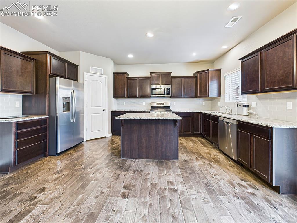 Image 14 of 50: Gourmet kitchen featuring dark espresso cabinetry, granite countertops, sta
