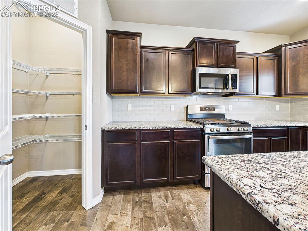 Image 15 of 50: View of the oversized walk-in pantry and sleek stainless gas range with bui