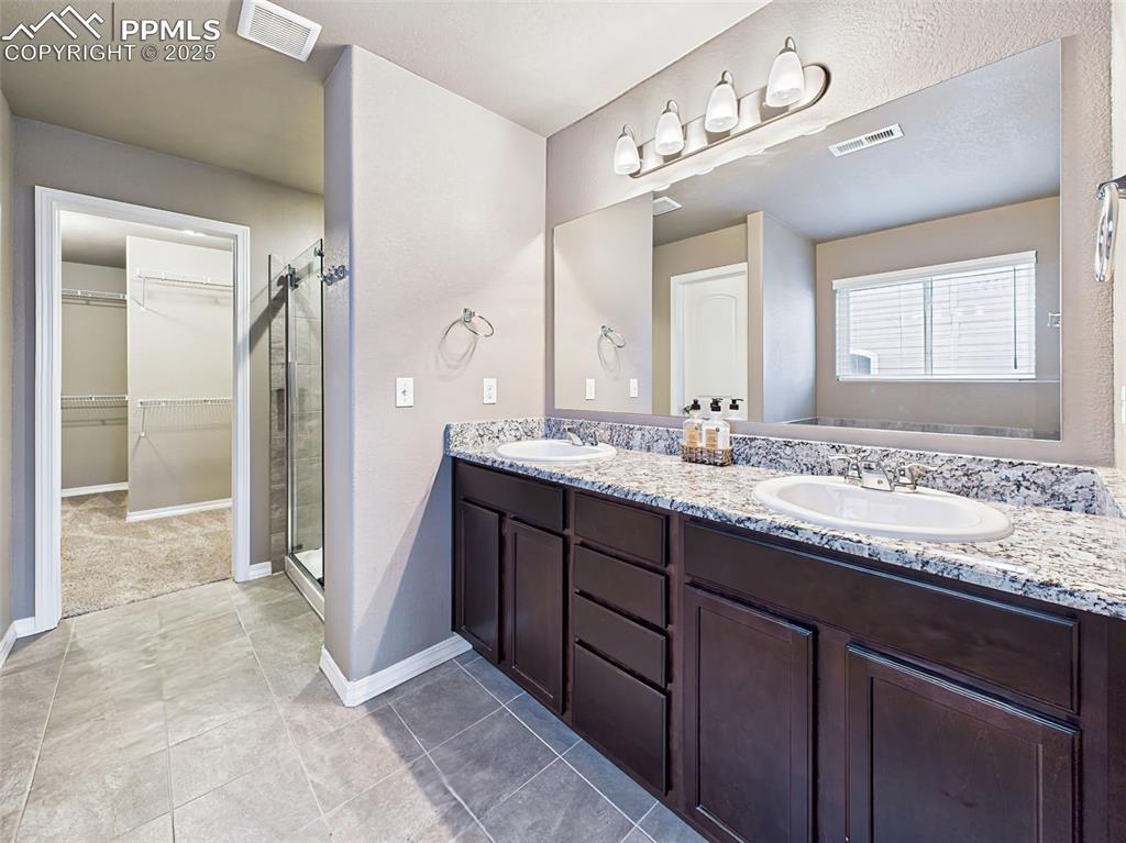 Image 29 of 50: En suite bath featuring dual sinks, granite countertops, walk-in shower, an
