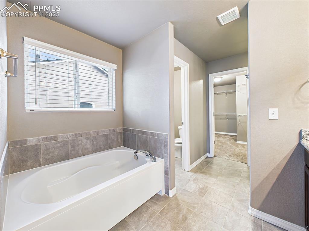 Image 30 of 50: Soaking Tub – Relaxing soaking tub with tile surround and a large window pr