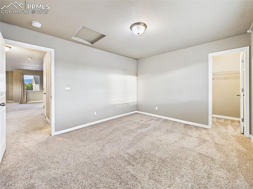 Image 33 of 50: Bright secondary bedroom with plush carpeting, soft wall tones, and ample n