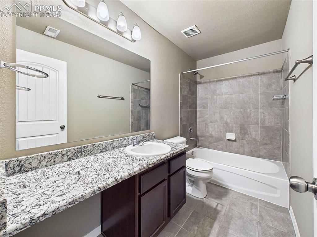 Image 37 of 50: Upper-level bath includes a granite-top vanity, modern tile flooring, and a