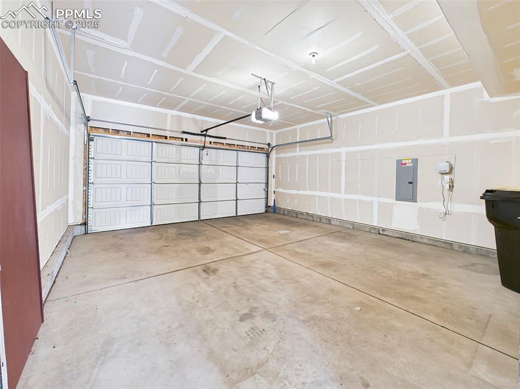 Image 39 of 50: Spacious two-car garage with finished drywall, automatic door opener, and p
