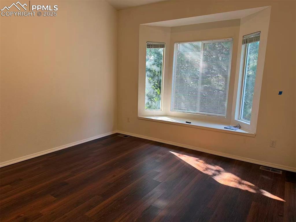 Image 11 of 13: Empty room with baseboards and dark wood-type flooring