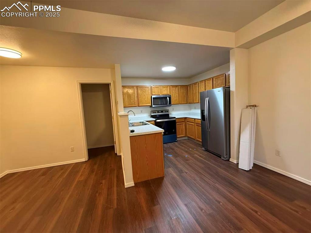 Image 2 of 13: Kitchen with light countertops, stainless steel appliances, brown cabinets,