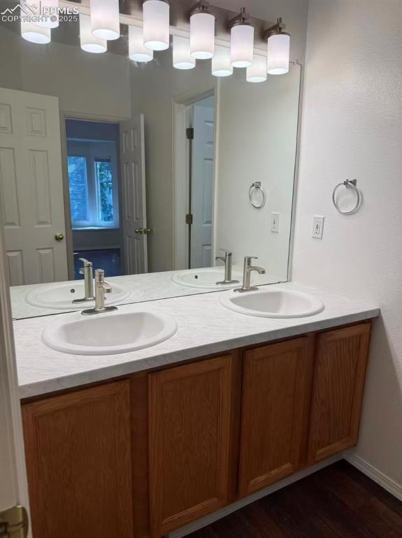 Image 5 of 13: Bathroom featuring double vanity and dark wood-style flooring