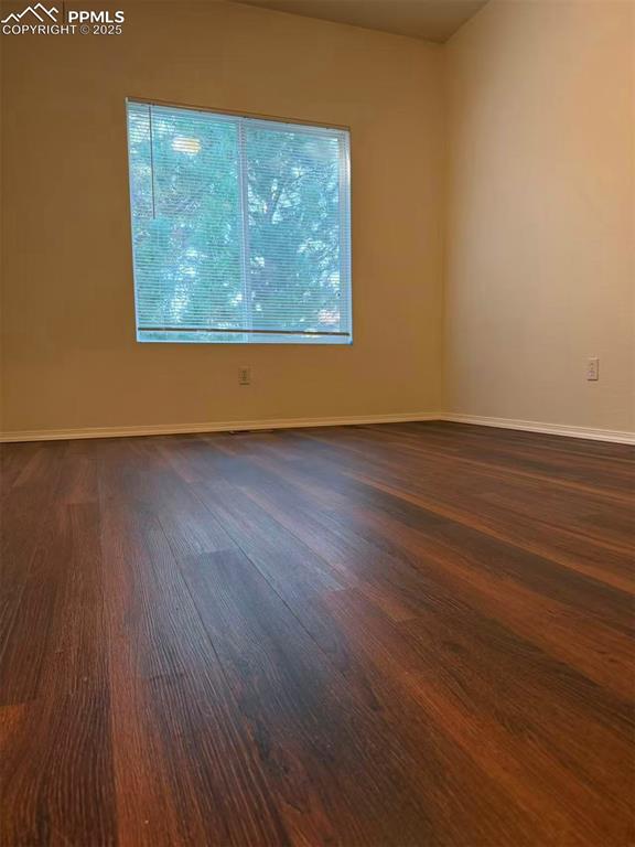 Image 8 of 13: Spare room with baseboards and dark wood-type flooring