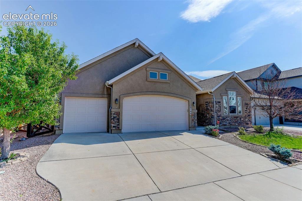 Image 1 of 50: Stucco exterior with stone accents, two attached garages, a concrete drivew