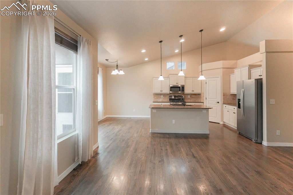 Image 10 of 44: Kitchen featuring stainless steel appliances, white cabinets, vaulted ceili