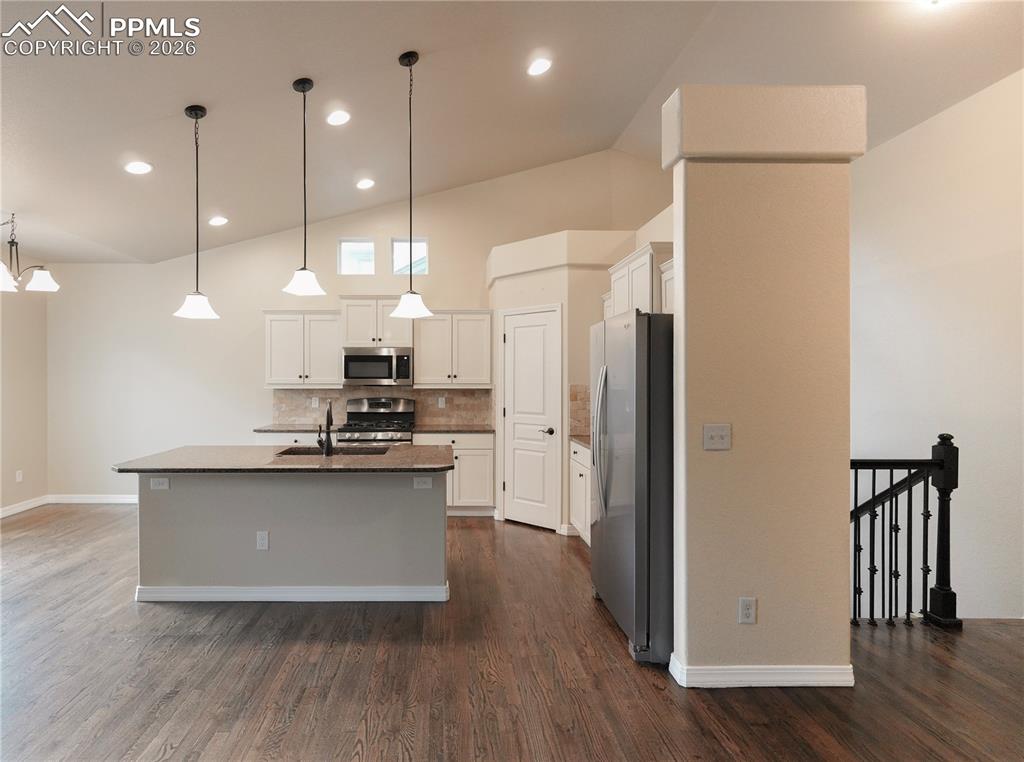 Image 11 of 44: Kitchen with stainless steel appliances, a kitchen island with sink, white 