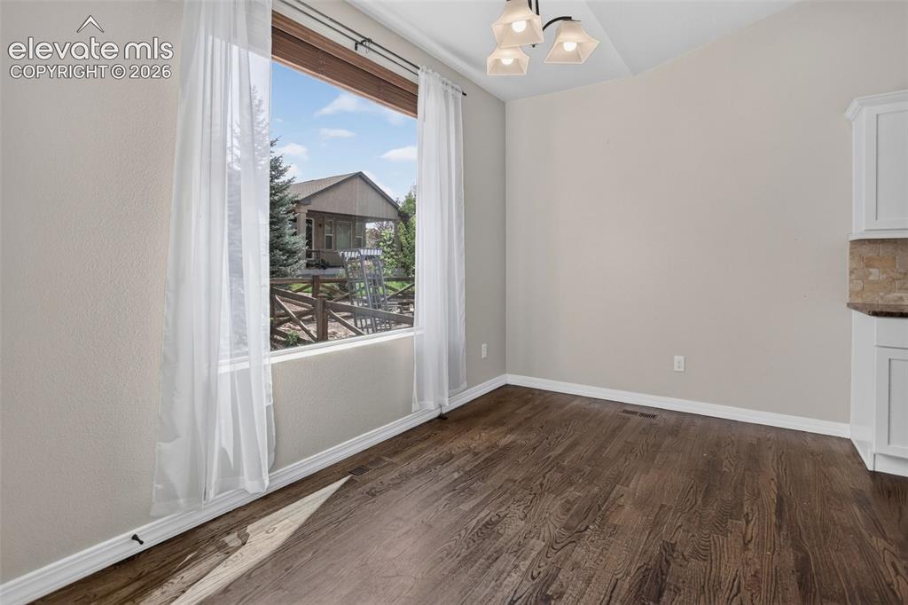 Image 11 of 50: Vaulted ceiling with an attached light fixture, wood-finish flooring, and a