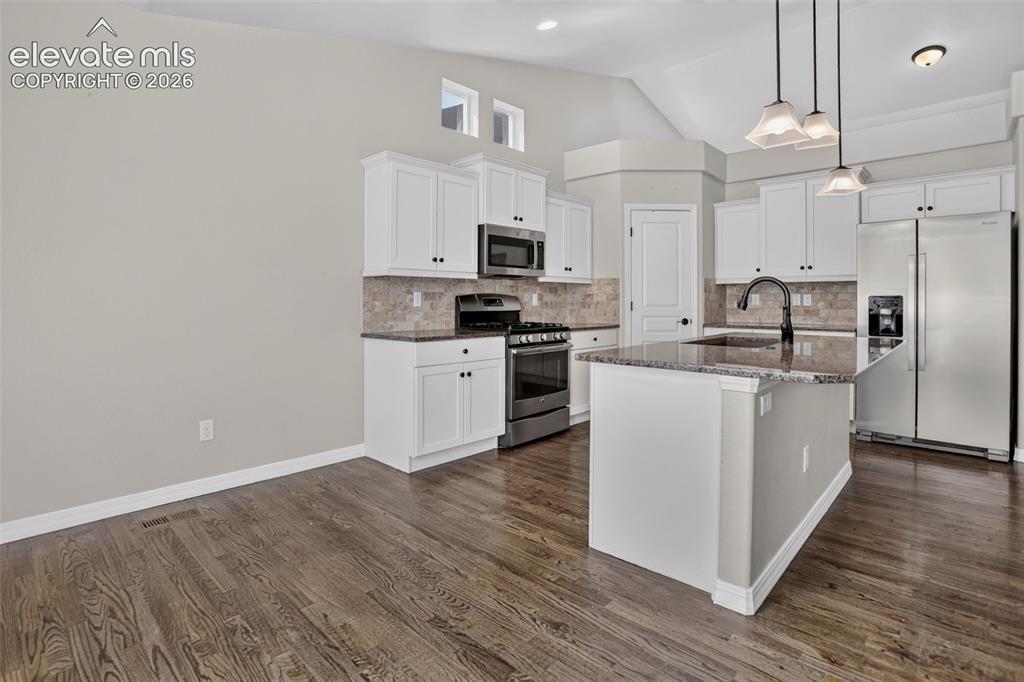 Image 13 of 50: Kitchen featuring wood-finish flooring, white cabinetry, a central island w