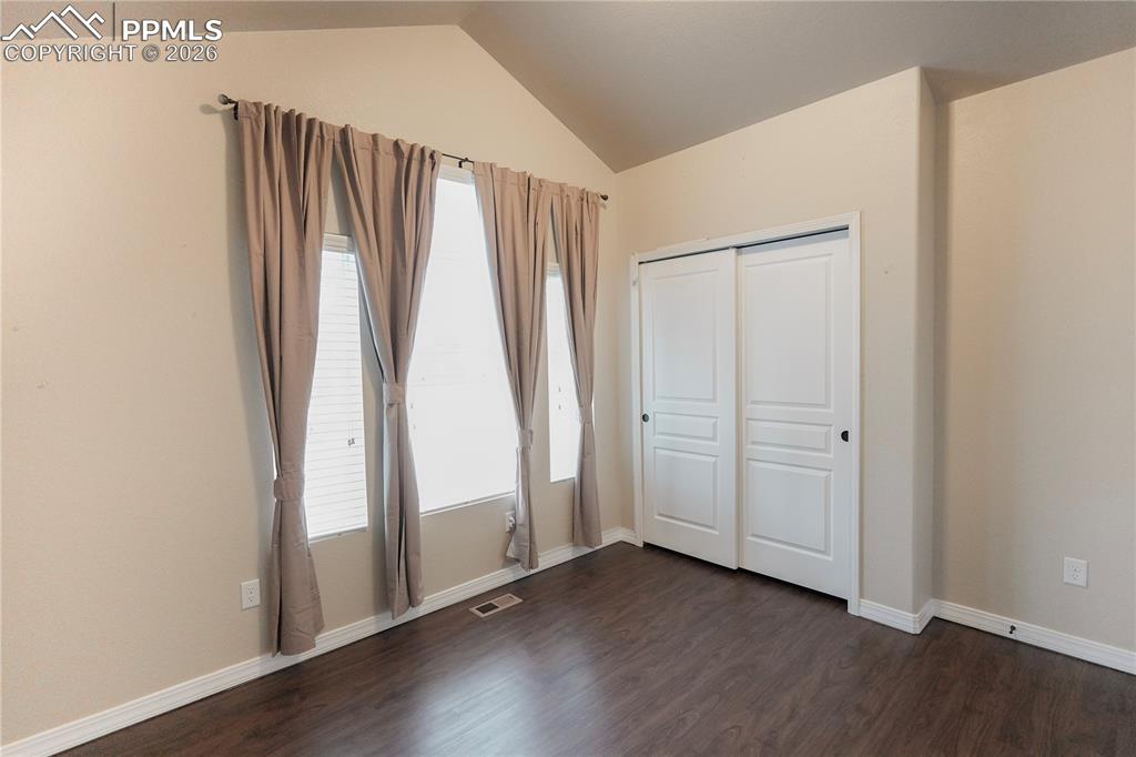 Image 14 of 44: Unfurnished bedroom with a closet, dark wood-style floors, and vaulted ceil