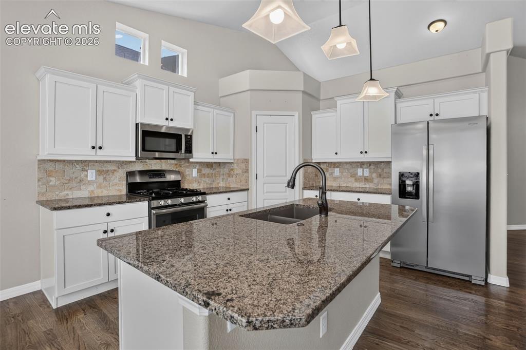 Image 14 of 50: Kitchen featuring an island with an undermount sink, granite countertops, w