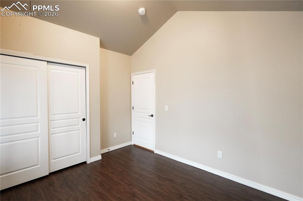 Image 15 of 44: Unfurnished bedroom featuring a closet, dark wood-style floors, and vaulted