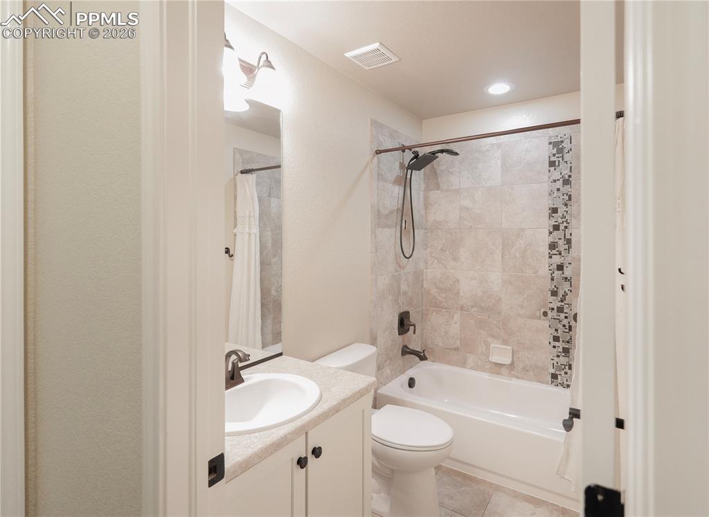 Image 16 of 44: Full bathroom with vanity, shower / tub combo with curtain, and light tile 