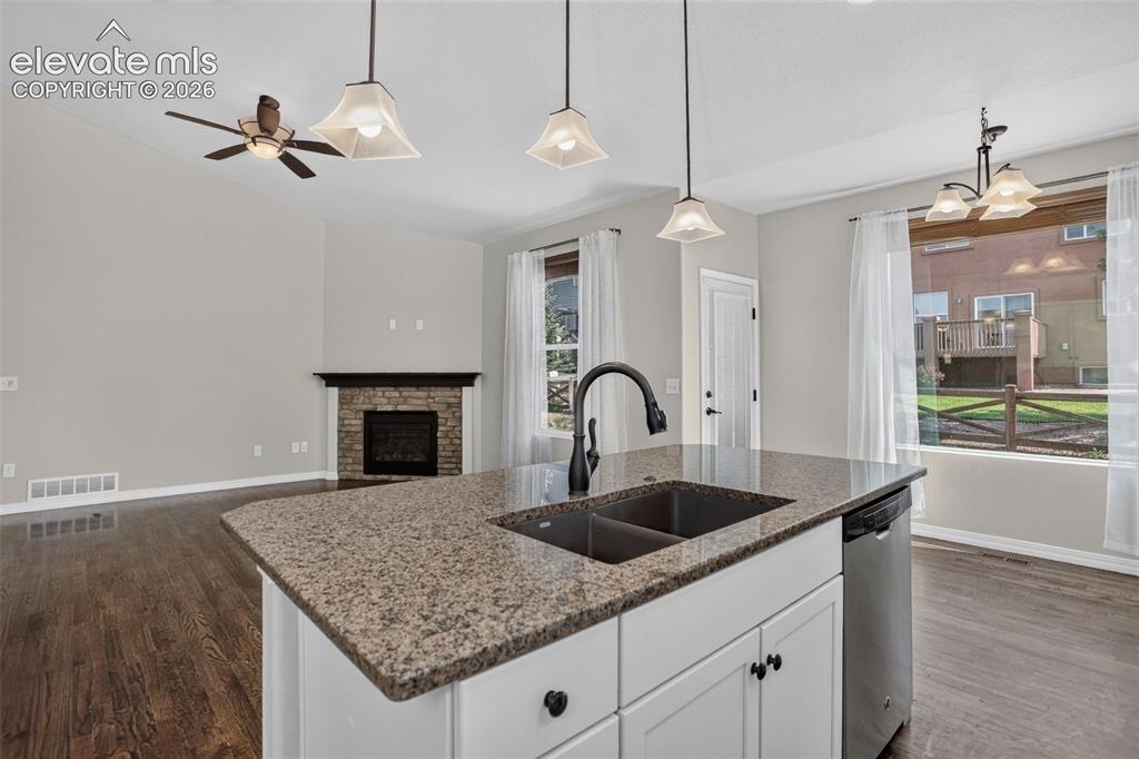 Image 16 of 50: Kitchen island with stone-finish countertop and undermount sink