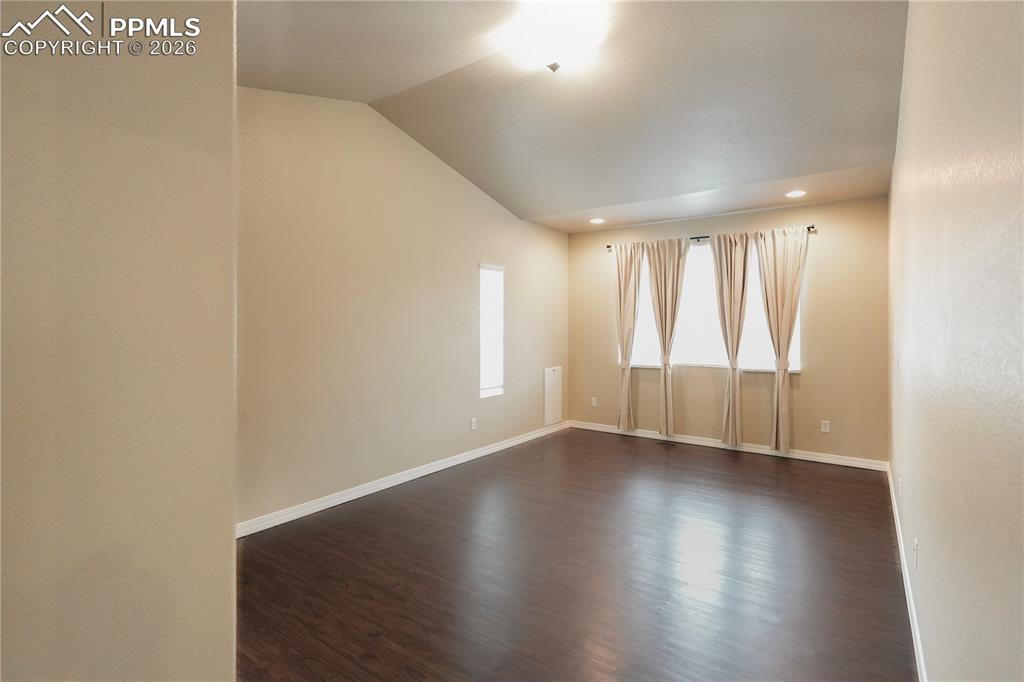 Image 19 of 44: Empty room featuring dark wood-type flooring, lofted ceiling, and recessed 