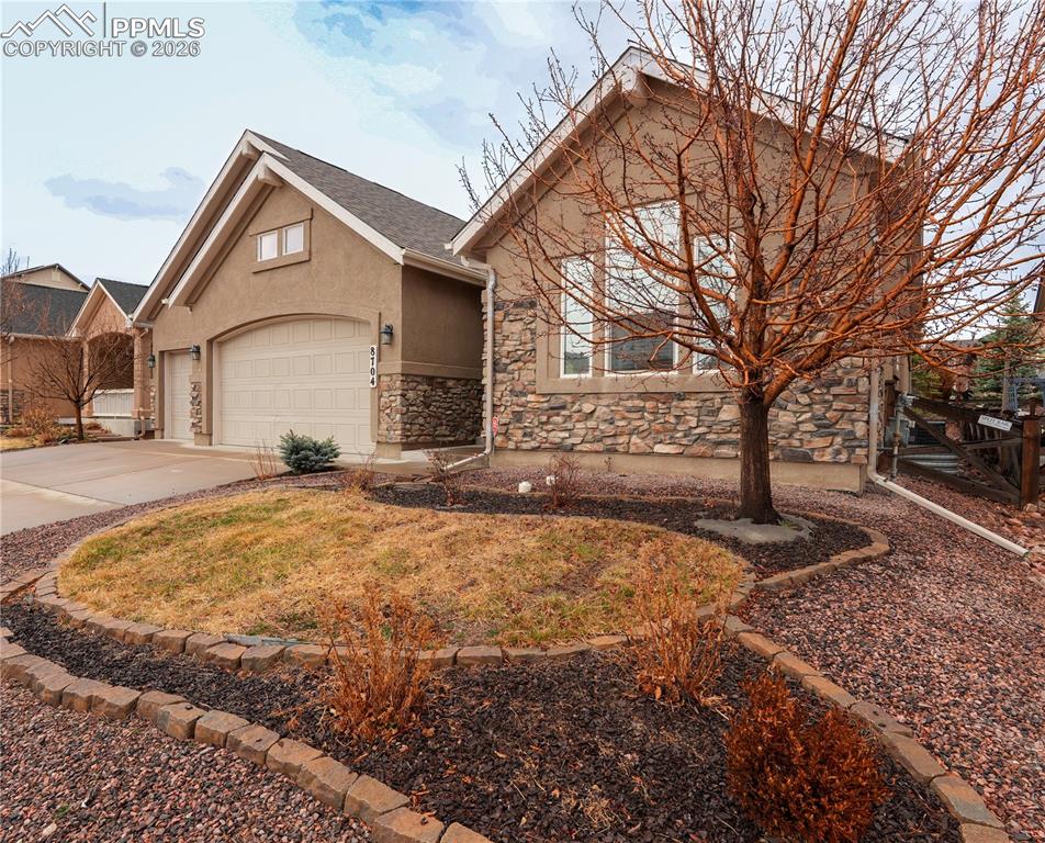 Image 2 of 44: View of front of house with driveway, stucco siding, stone siding, an attac