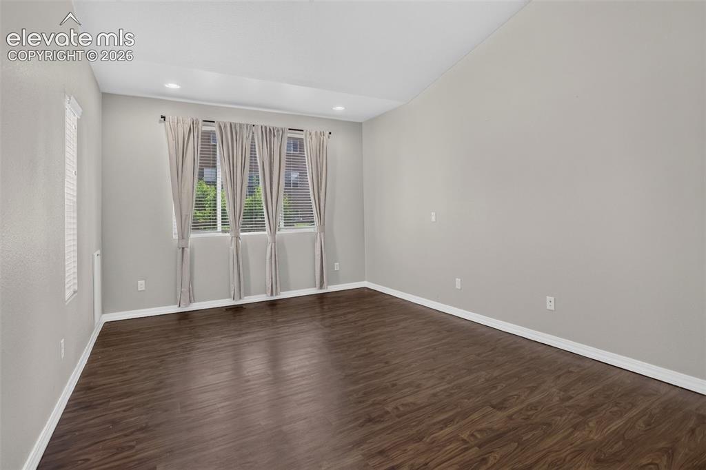 Image 21 of 50: Wood-finish flooring with light gray walls, multiple windows, and a vaulted
