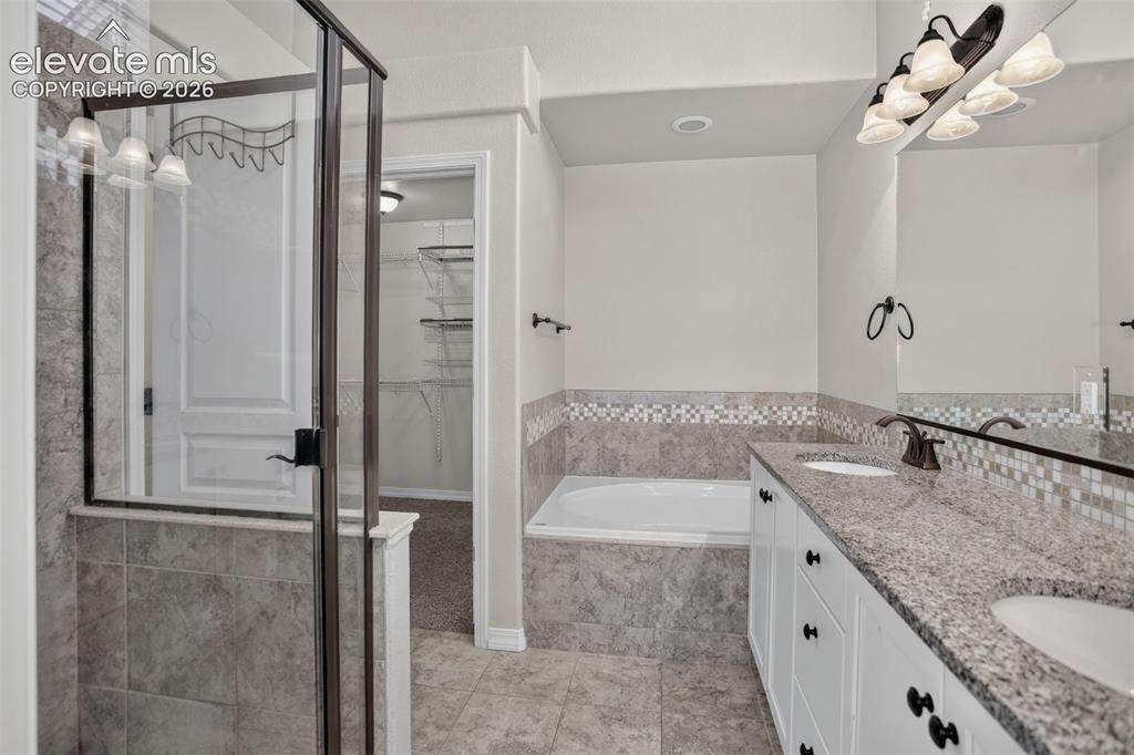 Image 23 of 50: Double vanity with integrated sinks, granite countertop, tile flooring, gla