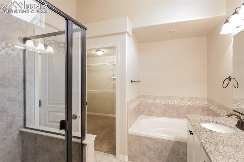 Image 25 of 44: Full bath with vanity, a spacious closet, a bath, and a shower stall