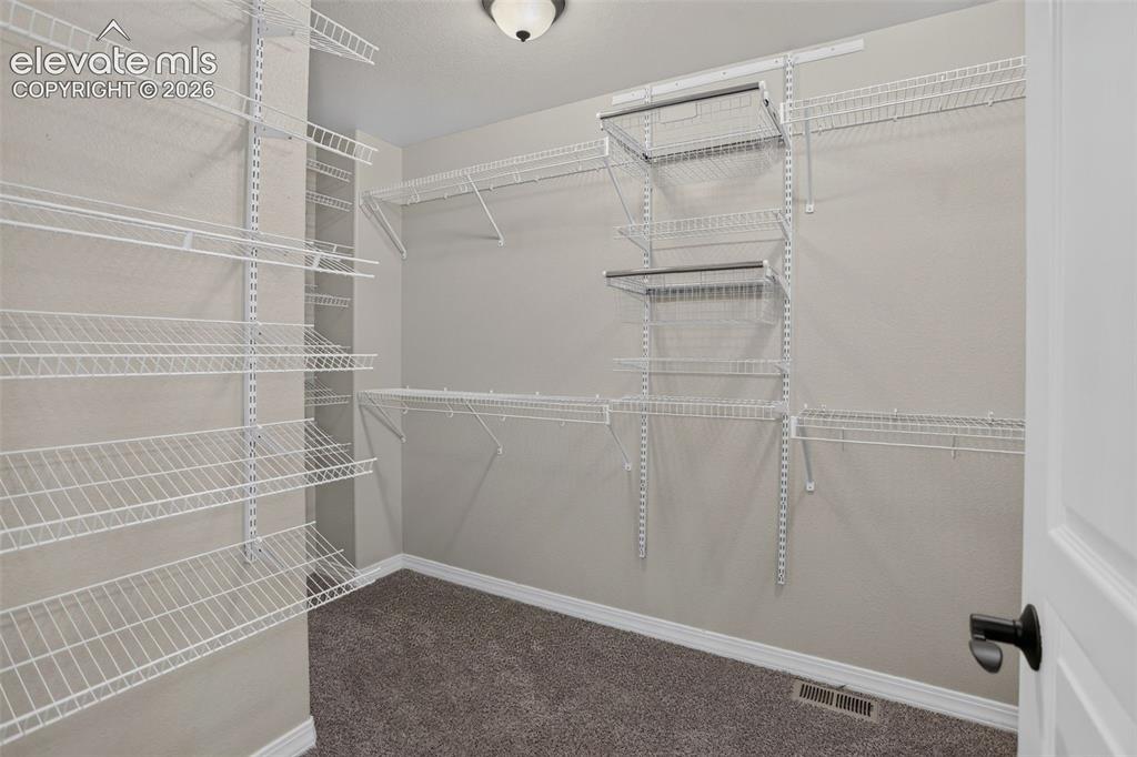Image 25 of 50: Spacious walk-in closet featuring white wire shelving throughout, multiple