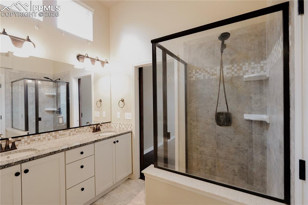Image 26 of 44: Full bath featuring double vanity, a stall shower, a high ceiling, and ligh
