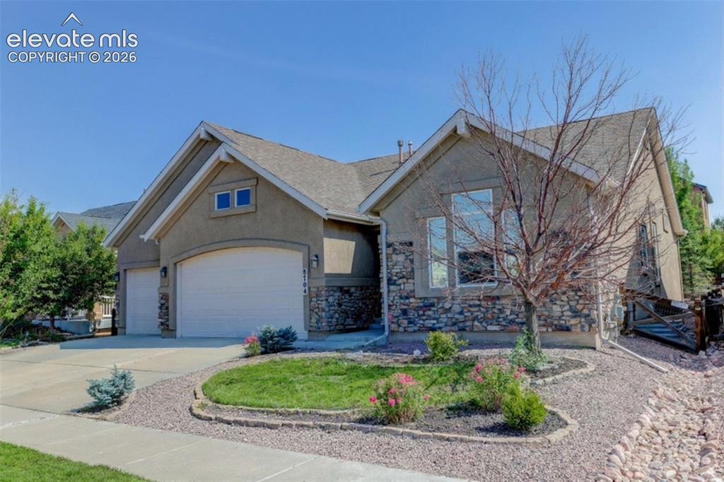 Image 3 of 50: Stucco exterior with stone accents, an arched two-car garage, established l
