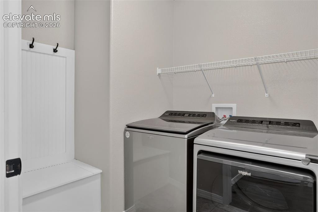 Image 31 of 50: Built-in storage bench with coat hooks, wire shelving, and light gray walls