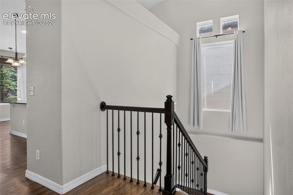 Image 32 of 50: Wood-finish flooring, staircase with dark wood newel post and wrought iron