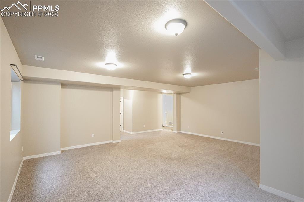 Image 34 of 44: Finished below grade area with a textured ceiling and light colored carpet
